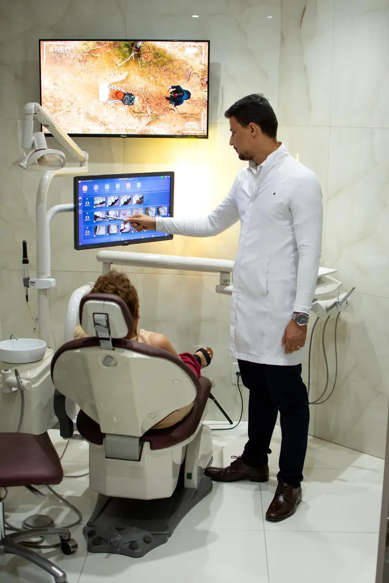 Dentista explicando o planejamento ao paciente na tela do consultório